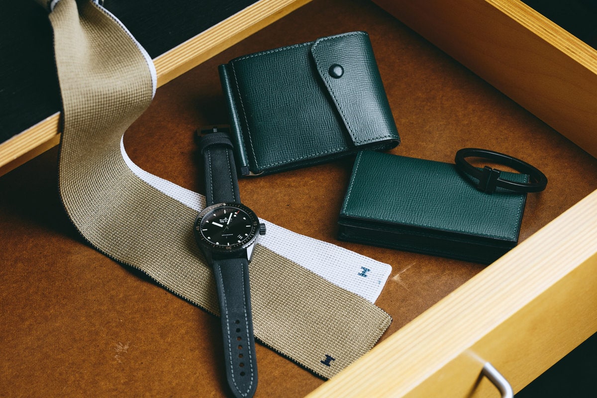 財布とカードケースはレザーアイテムを専門に扱うイタリアのブランド「ヴァレクストラ（Valextra）」のもの。1本で4色のパターンが楽しめる「エルメス（Hermès）」のニットタイ。腕時計は「ブランパン（BLANCPAIN）」のバチスカーフ。他にも数本所有。ブレスレットは「ティファニー（Tiffany & Co.）」のTスクエア。