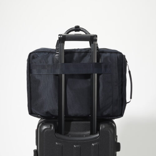 トートバッグ背面には、キャリーケースのハンドル部分に連結可能な面ファスナーを採用。出張の際に便利な機能性を備える。