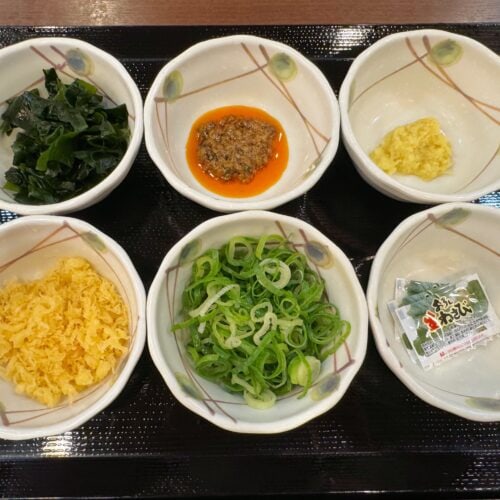 従来の6種類の薬味（青ねぎ、おろししょうが、天かす、香七味、すりごま、わさび）に加えて、新たにわかめとしび辛ラー油が追加され、全8種の展開になった無料の薬味＆トッピング
