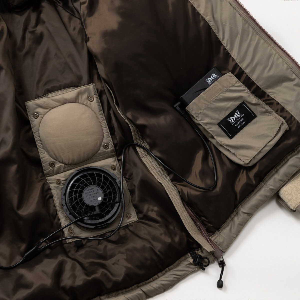 空調服の冷却システムを装備させつつも、ファンを外した状態でも通常のダウンジャケットとしても着⽤できるよう、ファン⽤の⽳を隠す機能を備えている。