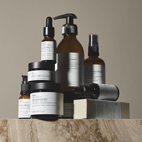 大理石のような台の上にEvolve Organic Beautyの複数の製品が積み重ねられている様子を写しています。