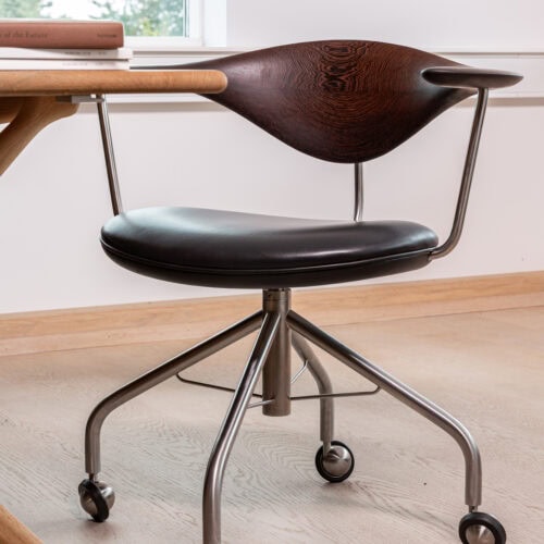 ウェグナー PP502 スウィベルチェア。濃い色の木製背もたれと黒いレザー座面、キャスター付きのステンレススチール脚。