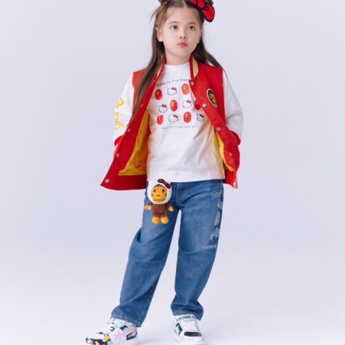 「Welcome to The Bape® World! のグラフィックをベースに、ハローキティがAPE HEADと出会うデザイン。左上にはMAD FACEを配置し、対角線上のハローキティもMAD FACEの表情にすることで、BAPE®ならではの遊び心をプラス。背面には尻尾を配し、後ろ姿にもアクセントを。