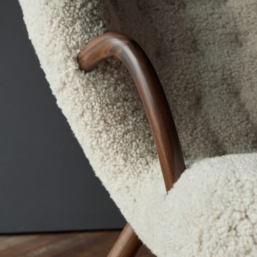 Clam Chairのシープスキン。オフホワイトのシープスキンを張ったムササビチェアのディテール。ダークウォールナットの曲線アームと脚。北欧のラウンジチェア。