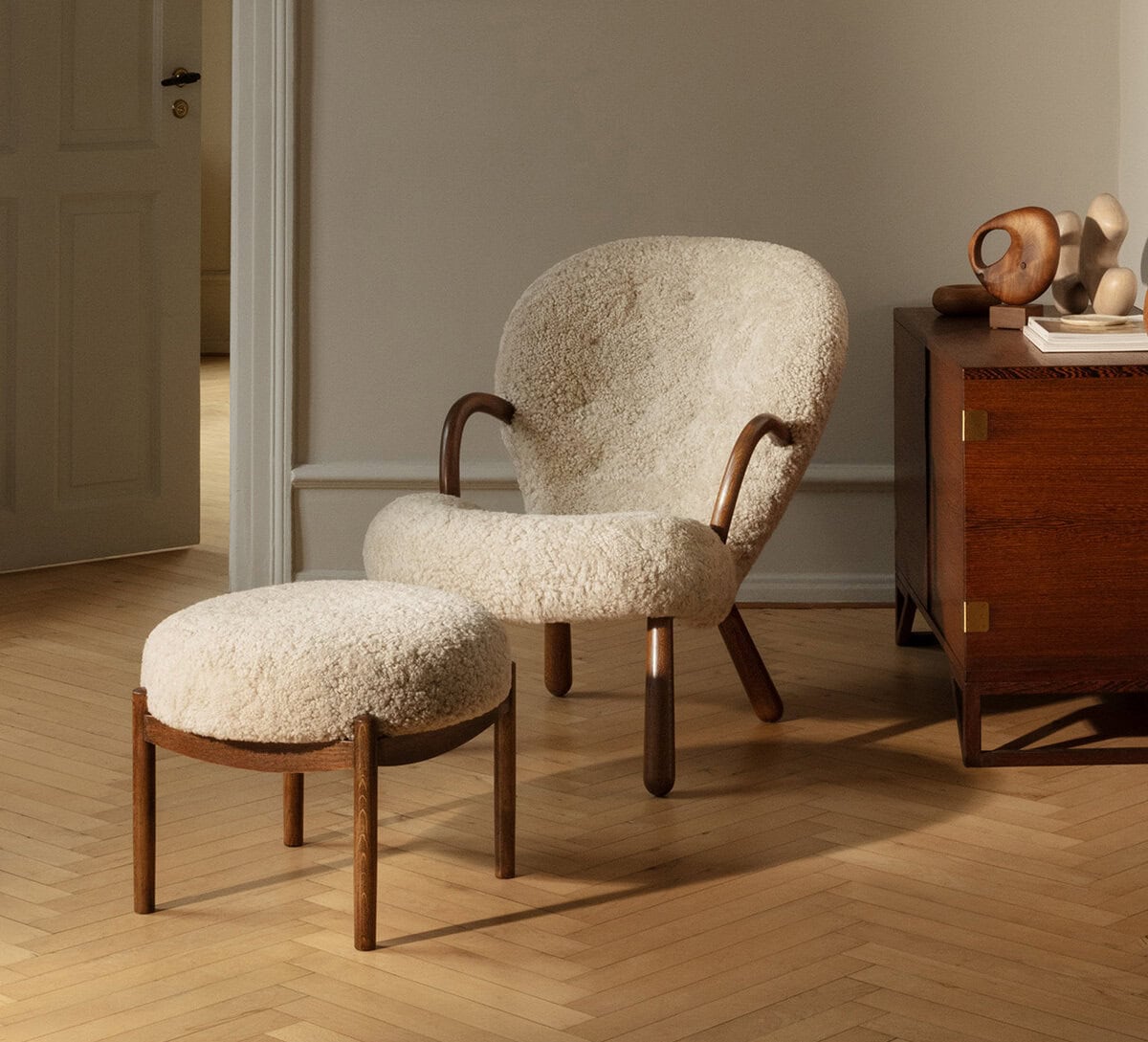 The Clam Chair。羊毛シープスキンを張った北欧ヴィンテージのラウンジチェアとオットマンのセット。ヘリンボーンのフローリング。