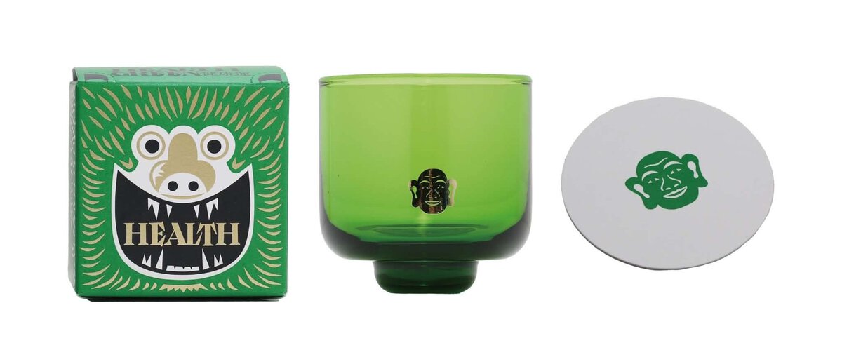緑色の陶器のカップとキャラクターのロゴ入りコースター.