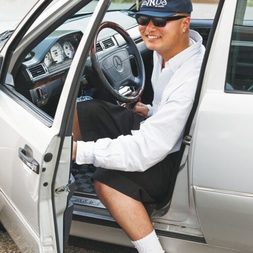 若者が車の運転席に座る笑顔の男性.